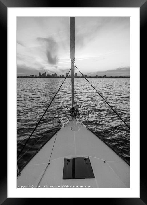 Bow of yacht sailing towards cityscape at sunrise Framed Mounted Print by Spotmatik 