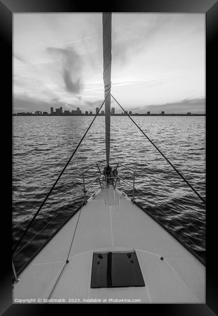 Bow of yacht sailing towards cityscape at sunrise Framed Print by Spotmatik 