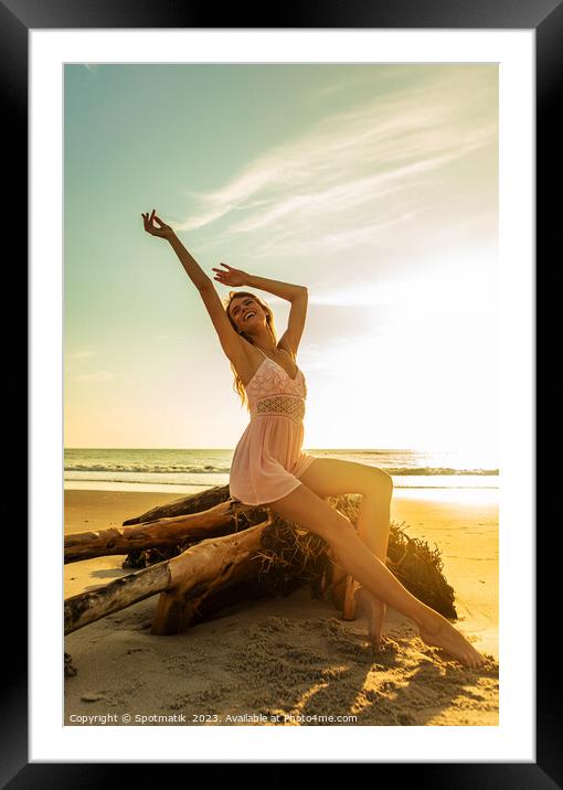 Carefree Bohemian girl sitting on driftwood at sunset Framed Mounted Print by Spotmatik 