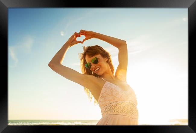 Bohemian girl showing heart sign dancing on beach Framed Print by Spotmatik 