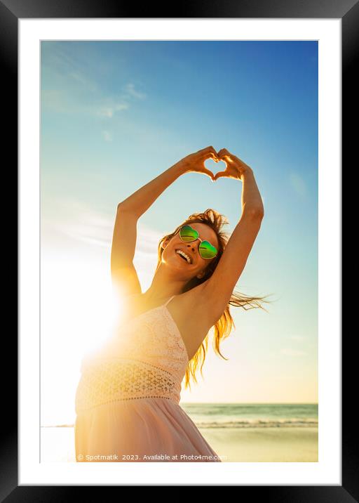 Bohemian girl dancing on beach showing heart sign Framed Mounted Print by Spotmatik 