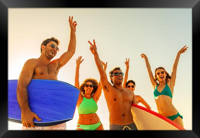 Friends enjoying carefree fun going bodyboarding on beach Framed Print by Spotmatik 
