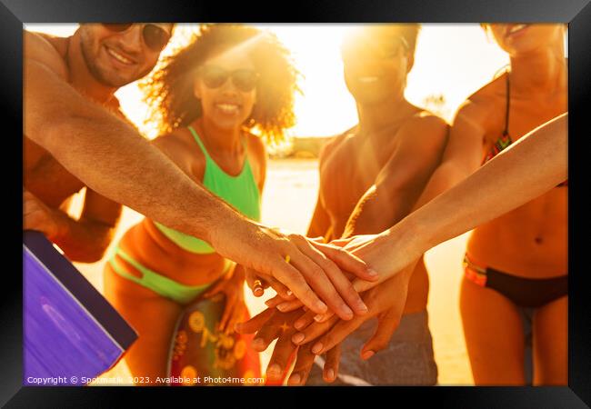 Friends in swimwear joining hands on beach vacation Framed Print by Spotmatik 