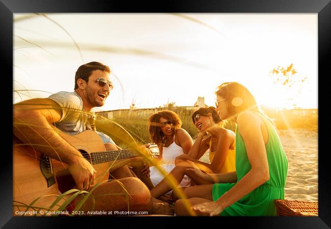 Young friends enjoying guitar music on beach vacation Framed Print by Spotmatik 
