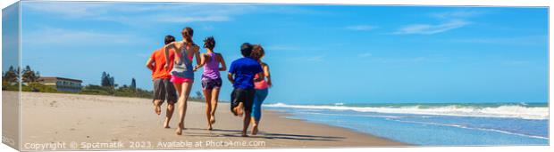 Panoramic view of friends jogging together on beach Canvas Print by Spotmatik 