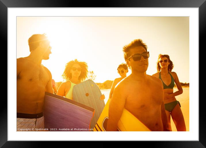 Friends in swimwear carrying bodyboards enjoying Summer vacation Framed Mounted Print by Spotmatik 