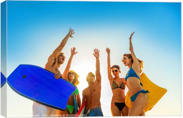 Friends in swimwear carrying bodyboards celebrating fun activity Canvas Print by Spotmatik 