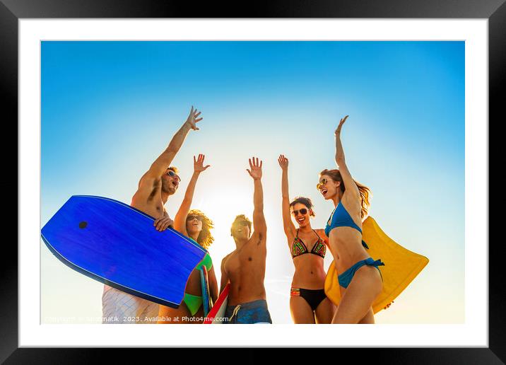Friends in swimwear carrying bodyboards celebrating fun activity Framed Mounted Print by Spotmatik 