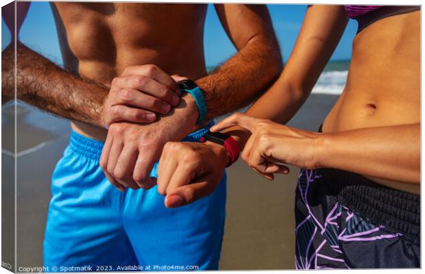 Fit young couple on beach setting activity trackers Canvas Print by Spotmatik 
