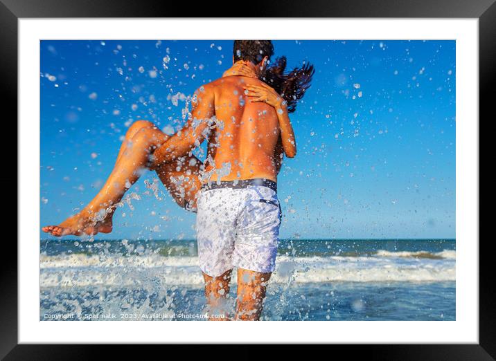 Fun loving ethnic couple running in ocean waves Framed Mounted Print by Spotmatik 