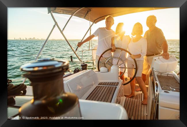 Senior friends enjoying retirement steering yacht at sunset Framed Print by Spotmatik 