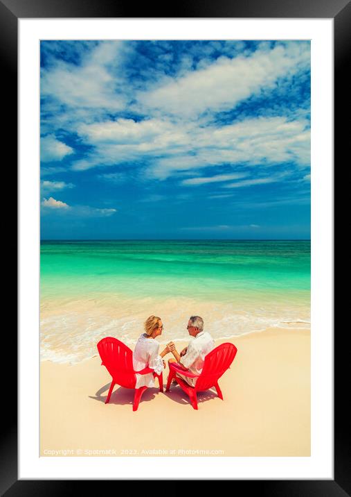 Mature couple on red chairs by ocean Bahamas Framed Mounted Print by Spotmatik 