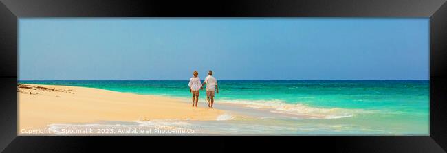 Panoramic view mature couple walking on beach Bahamas Framed Print by Spotmatik 