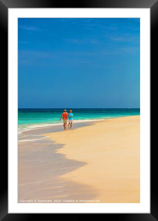 Tropical island shoreline with retired couple walking barefoot Framed Mounted Print by Spotmatik 