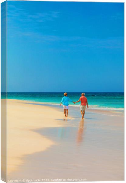 Retired couple holding hands enjoying walk on beach Canvas Print by Spotmatik 