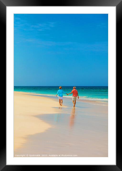 Retired couple holding hands enjoying walk on beach Framed Mounted Print by Spotmatik 