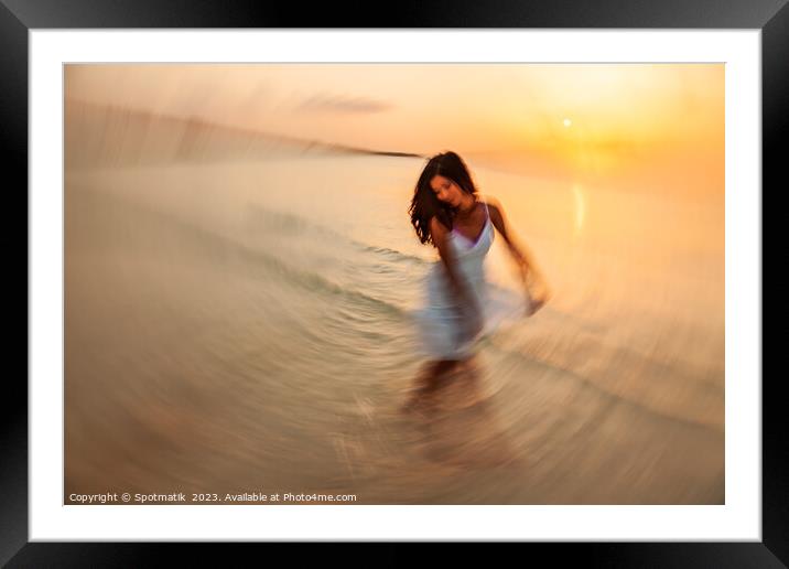 Motion blurred dancing Asian girl in ocean sunset Framed Mounted Print by Spotmatik 