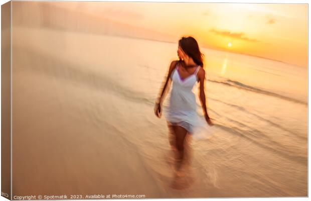Motion blurred woman walking through waves at sunset Canvas Print by Spotmatik 
