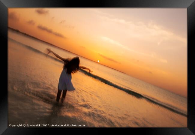 Motion blur girl standing in ocean at sunrise Framed Print by Spotmatik 