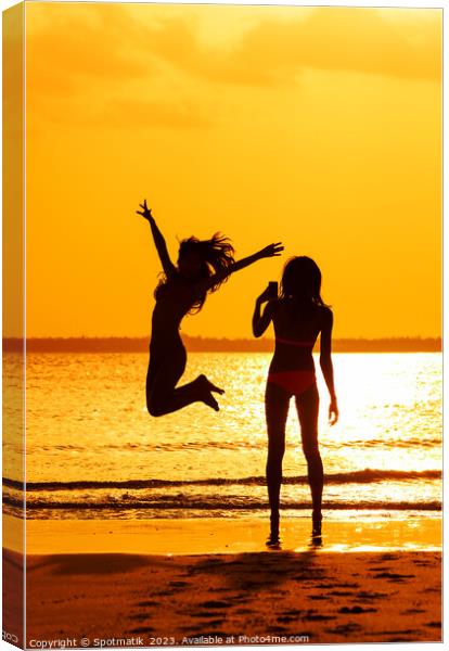 Tropical ocean sunrise with girl photographing friend jumping Canvas Print by Spotmatik 