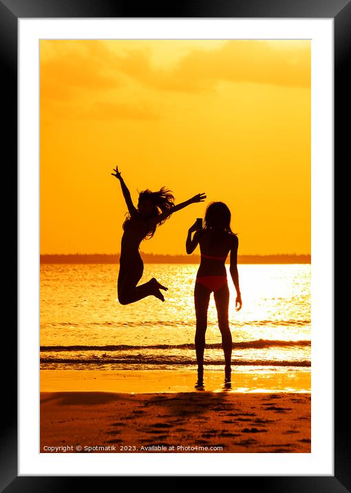 Tropical ocean sunrise with girl photographing friend jumping Framed Mounted Print by Spotmatik 