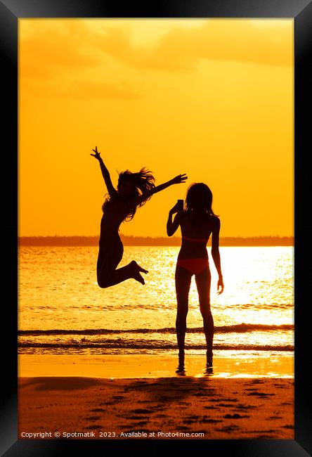 Tropical ocean sunrise with girl photographing friend jumping Framed Print by Spotmatik 