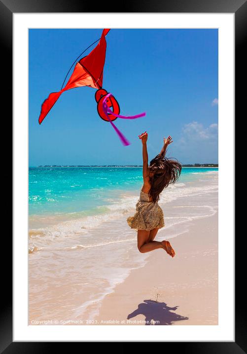 Happy Asian girl jumping by ocean flying kite Framed Mounted Print by Spotmatik 