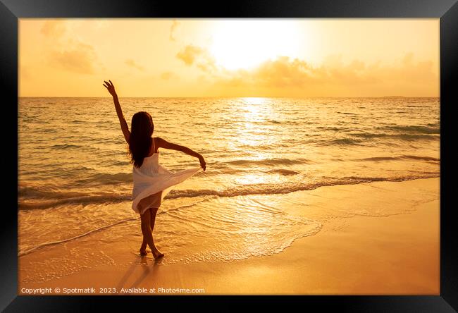 Asian girl standing in ocean waves at sunrise Framed Print by Spotmatik 