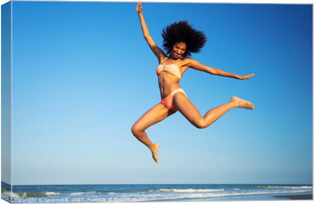 Fun loving Afro female jumping by the ocean Canvas Print by Spotmatik 
