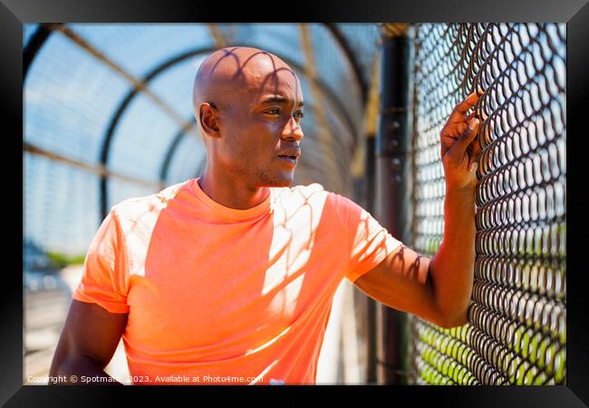 African American male resting against chain link fence Framed Print by Spotmatik 