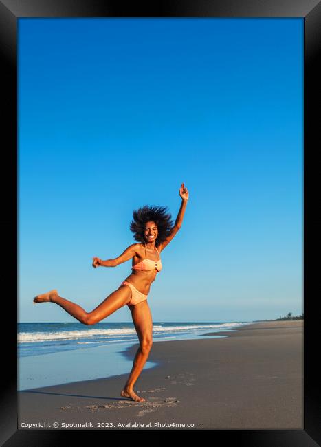 Playful young Afro American woman by the ocean Framed Print by Spotmatik 