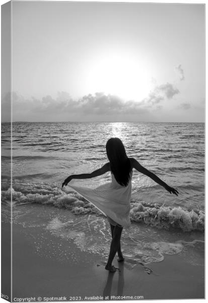 Asian girl with arms outstretched by the ocean Canvas Print by Spotmatik 