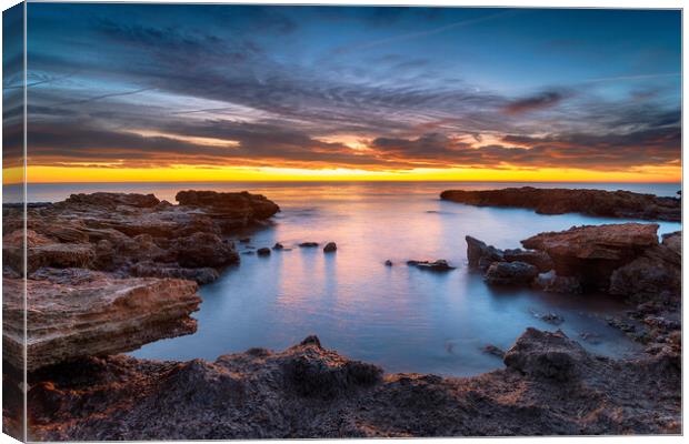 Beautiful sunrise over rocks at the beach at Torre de la Sal Canvas Print by Helen Hotson