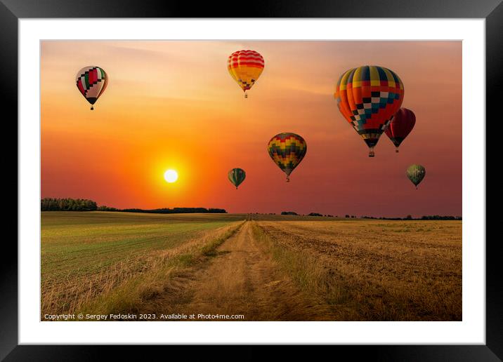 Colorful hot air balloons flying over field at sunset. Framed Mounted Print by Sergey Fedoskin