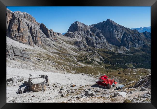 Tourist with hiking backpacks in mountain hike on summer day. Man traveler hiking in beautiful mountain landscape. Climber and alpine hut Silvio Agostini in Dolomites Alps, Italy. Framed Print by Lubos Chlubny