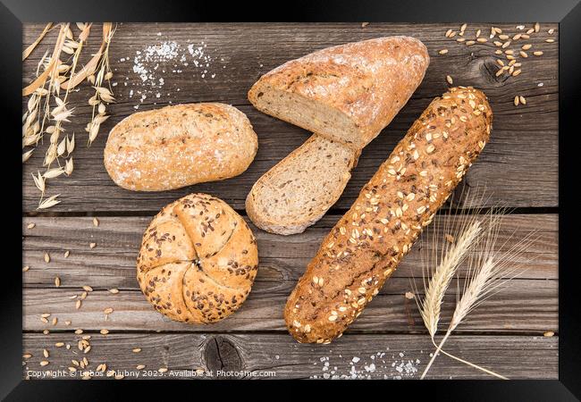 Background of fresh bread and bakery on an old vintage planked wood table. Framed Print by Lubos Chlubny
