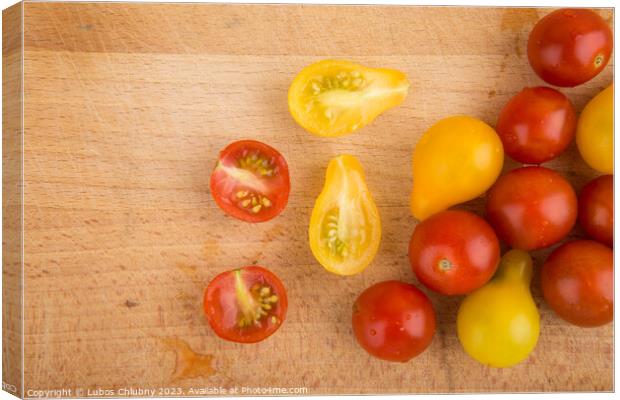 Red and yellow cherry tomatoes on a wooden cutting board Canvas Print by Lubos Chlubny