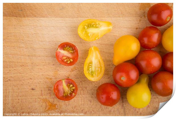 Red and yellow cherry tomatoes on a wooden cutting board Print by Lubos Chlubny