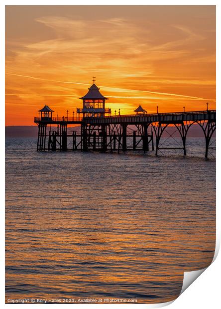 Clevedon pier at sunset with a reddish orangey glow Print by Rory Hailes