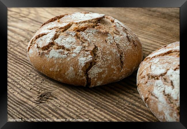 Delicious baked bread on a wooden background Framed Print by Lubos Chlubny