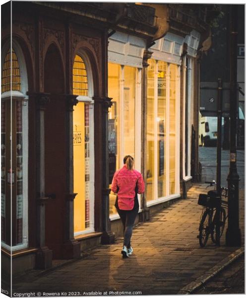 A jogger passing a warm shop front  Canvas Print by Rowena Ko