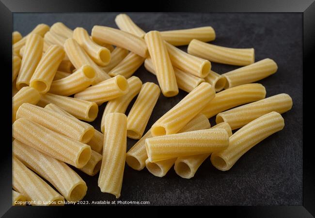 Raw italian penne rigate pasta isolated on black background Framed Print by Lubos Chlubny