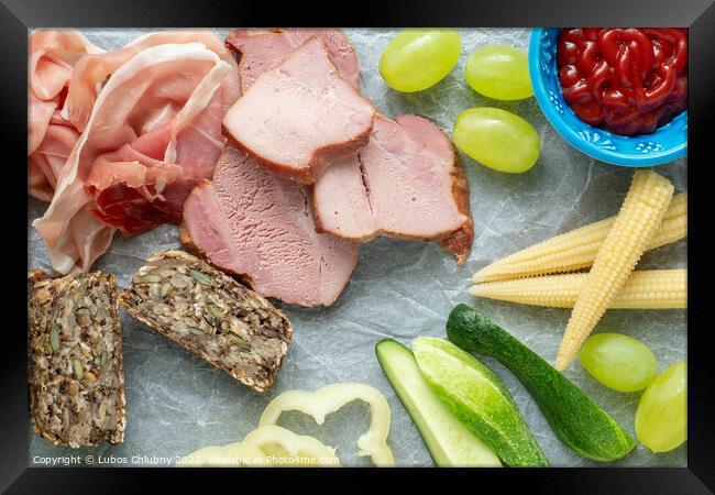 Cold appetizer. Cold cuts. Different snacks on a white crumpled paper, bacon, fruits, grapes, vegetables, from above. Framed Print by Lubos Chlubny