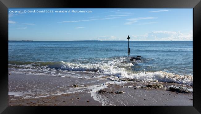 A rocky groyne on the sandy beach at Sandbanks Framed Print by Derek Daniel