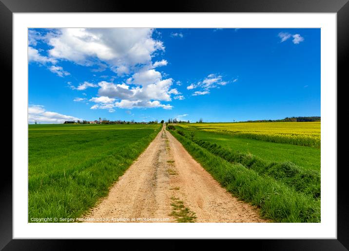 Rural dirt road among fields under the blue sky. Framed Mounted Print by Sergey Fedoskin