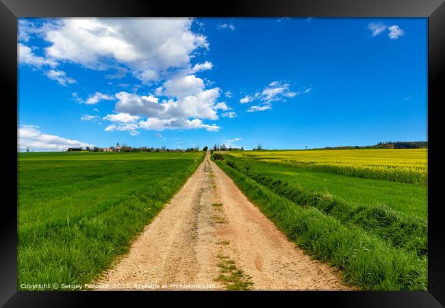 Rural dirt road among fields under the blue sky. Framed Print by Sergey Fedoskin