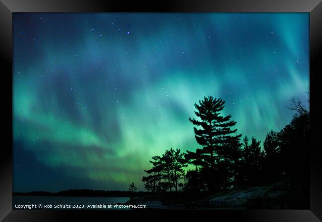 Northern lights erupt over a lake in Minnesota in a dark sky ove Framed Print by Rob Schultz
