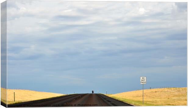 Lone biker on an empty rural road with 'Do Not Pass' sign in the foreground Canvas Print by Madeleine Deaton