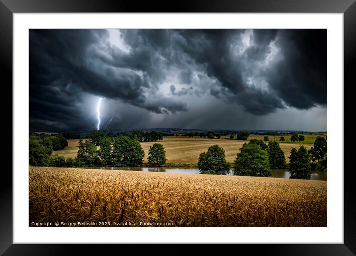 Lightning strike through the storm clouds over rural countryside. Framed Mounted Print by Sergey Fedoskin