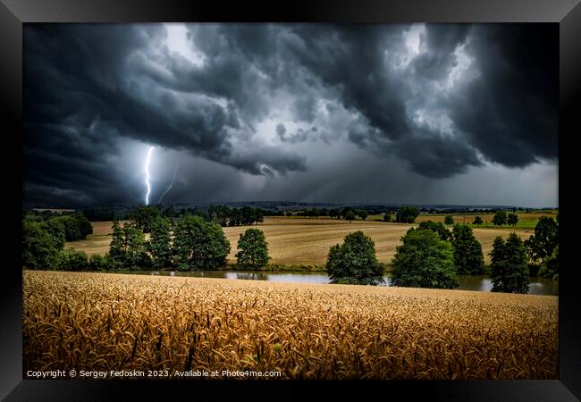 Lightning strike through the storm clouds over rural countryside. Framed Print by Sergey Fedoskin